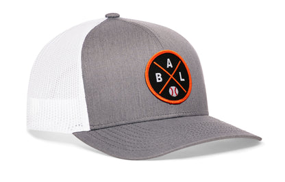 gray-white trucker hat viewed from the right side, showcasing a bold black and orange embroidered X patch prominently displayed on the front