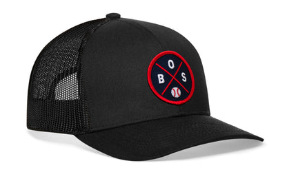 black trucker hat viewed from the right side, showcasing a navy and red baseball embroidered X patch prominently displayed on the front