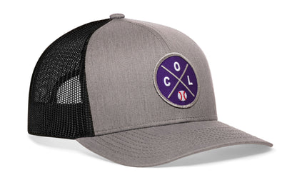 gray-black trucker hat viewed from the right side, showcasing a bold purple and gray embroidered X patch prominently displayed on the front