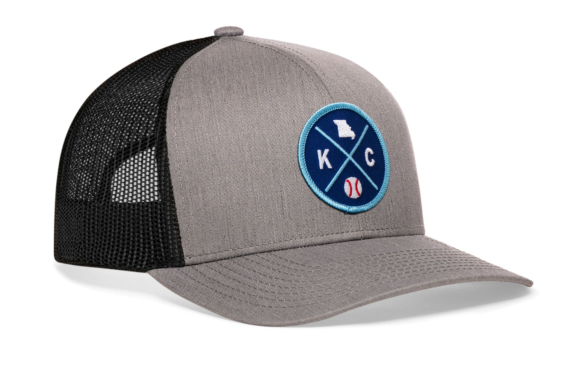 gray-black trucker hat viewed from the right side, showcasing a bold royal and columbia blue embroidered X patch prominently displayed on the front