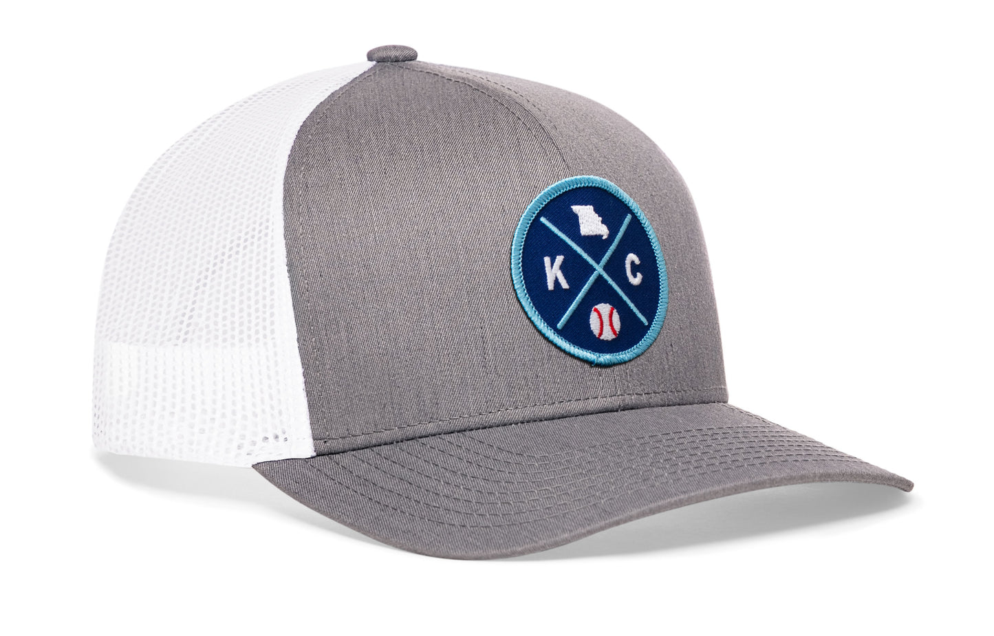 gray-white trucker hat viewed from the right side, showcasing a bold royal and columbia blue embroidered X patch prominently displayed on the front