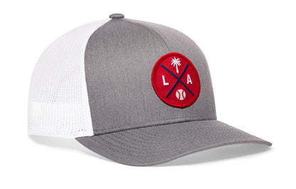 gray-white trucker hat viewed from the right side, showcasing a bold red and navy embroidered X patch prominently displayed on the front