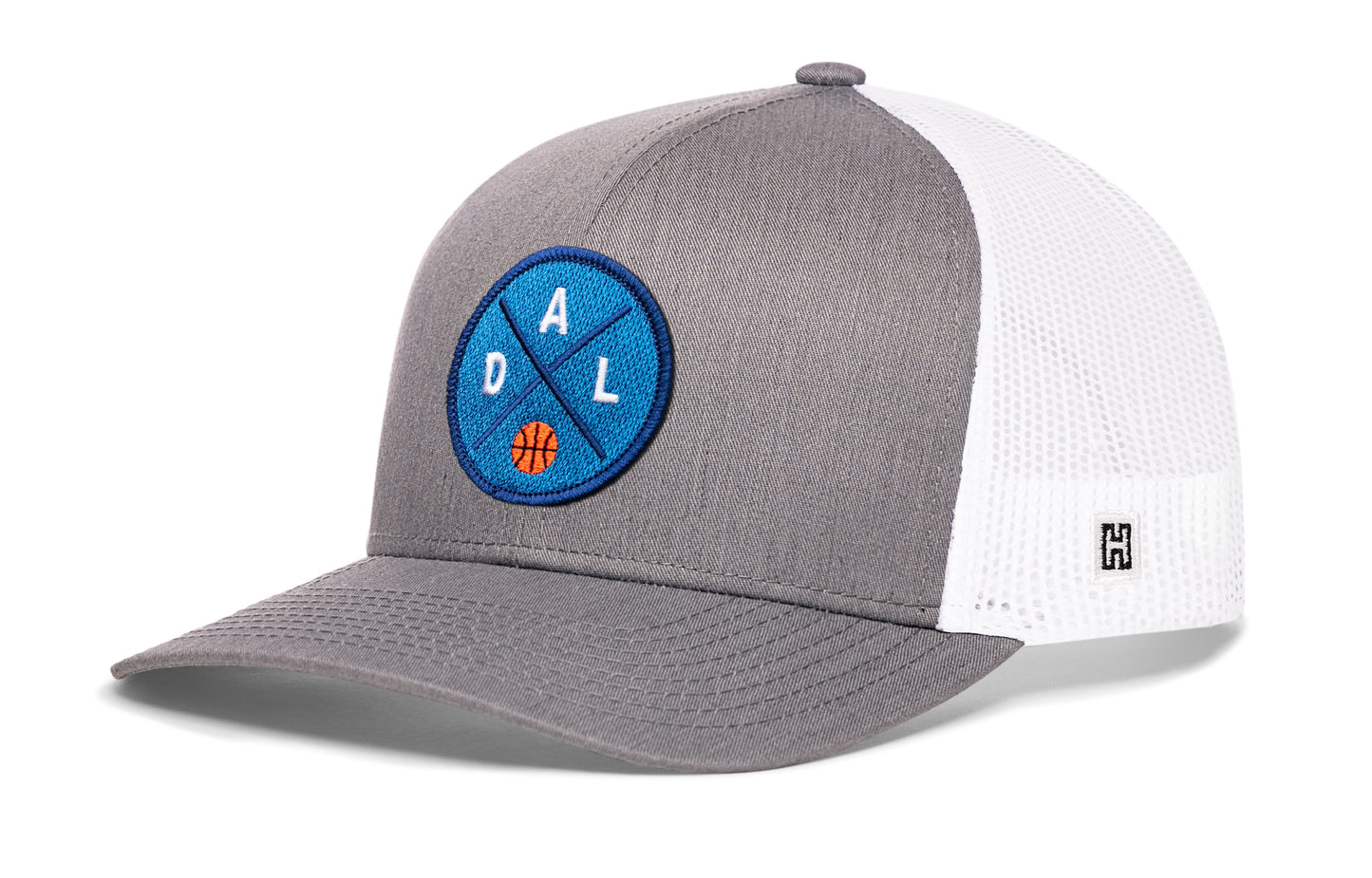 Dallas trucker hat, gray-white snapback showing Haka brandmark on left side mesh.
Rep Dallas, TX basketball.
