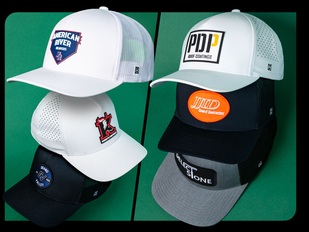 6 custom trucker and performance hats stacked each with their own custom designs for trades, schools and businesses.