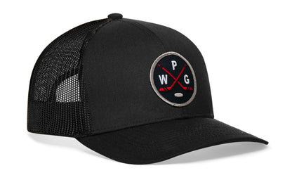 black trucker hat viewed from the right side, showcasing a navy, red and gray hockey embroidered X patch prominently displayed on the front