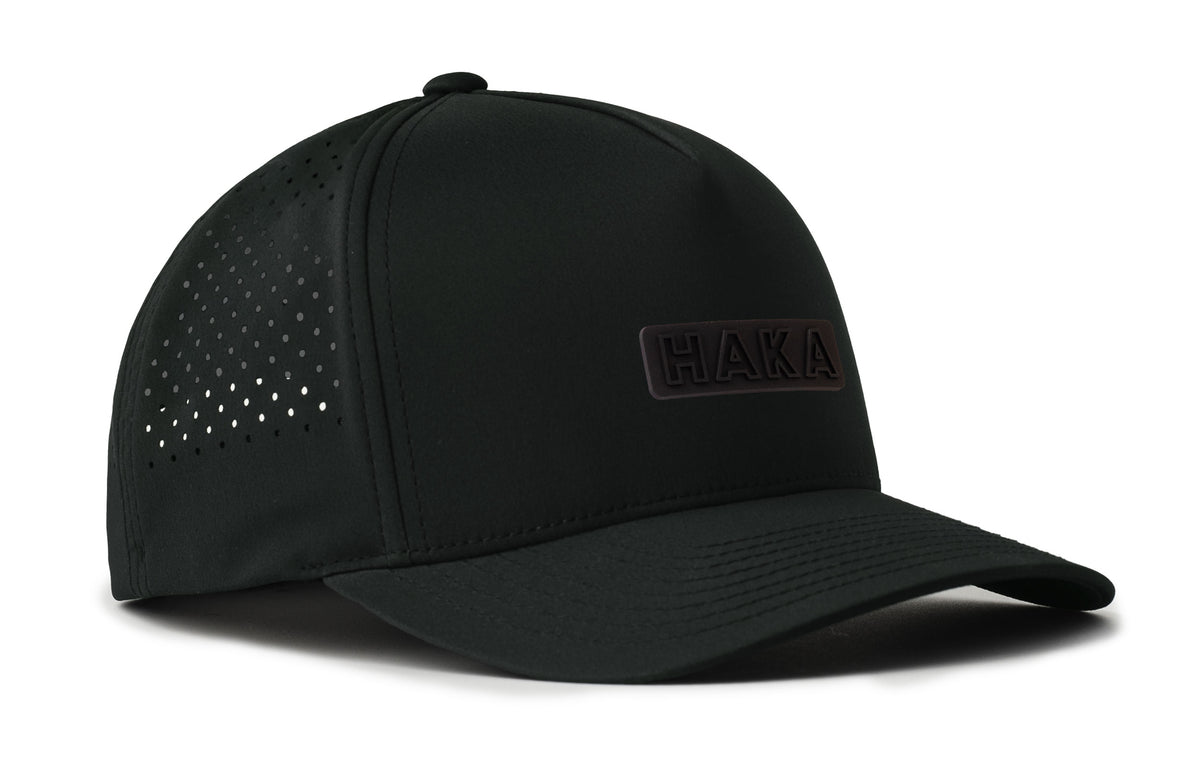 black performance 5-panel hat viewed from the right side, showcasing a bold black on black pvc patch prominently displayed on the front