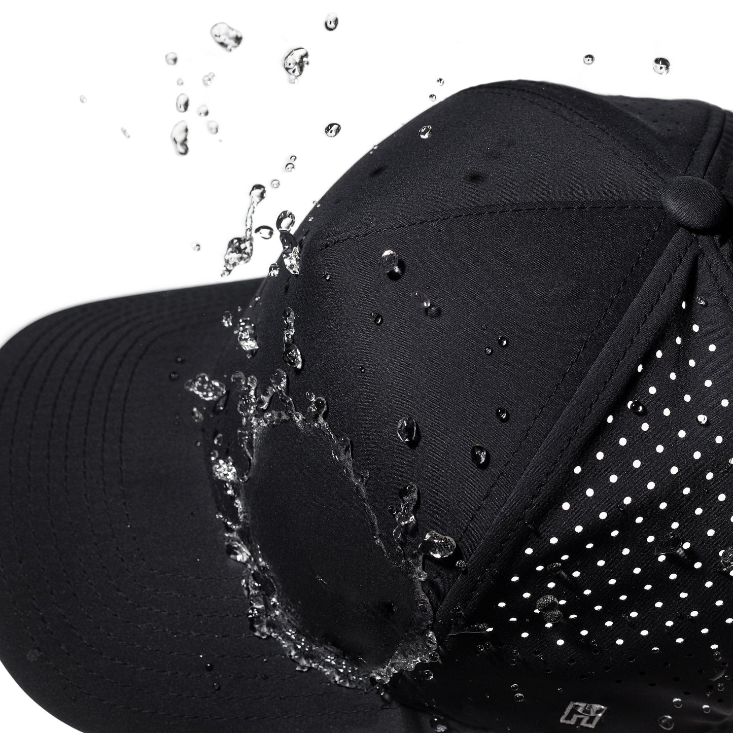 Black performance hat with water droplets splashing onto it against a white background