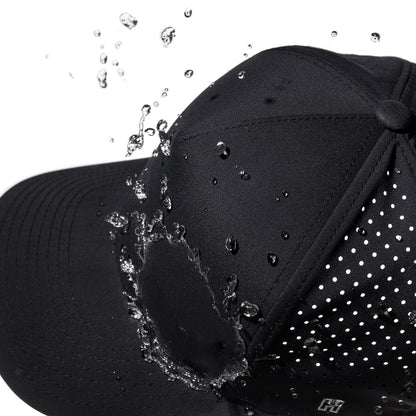 Black performance hat with water droplets splashing onto it against a white background