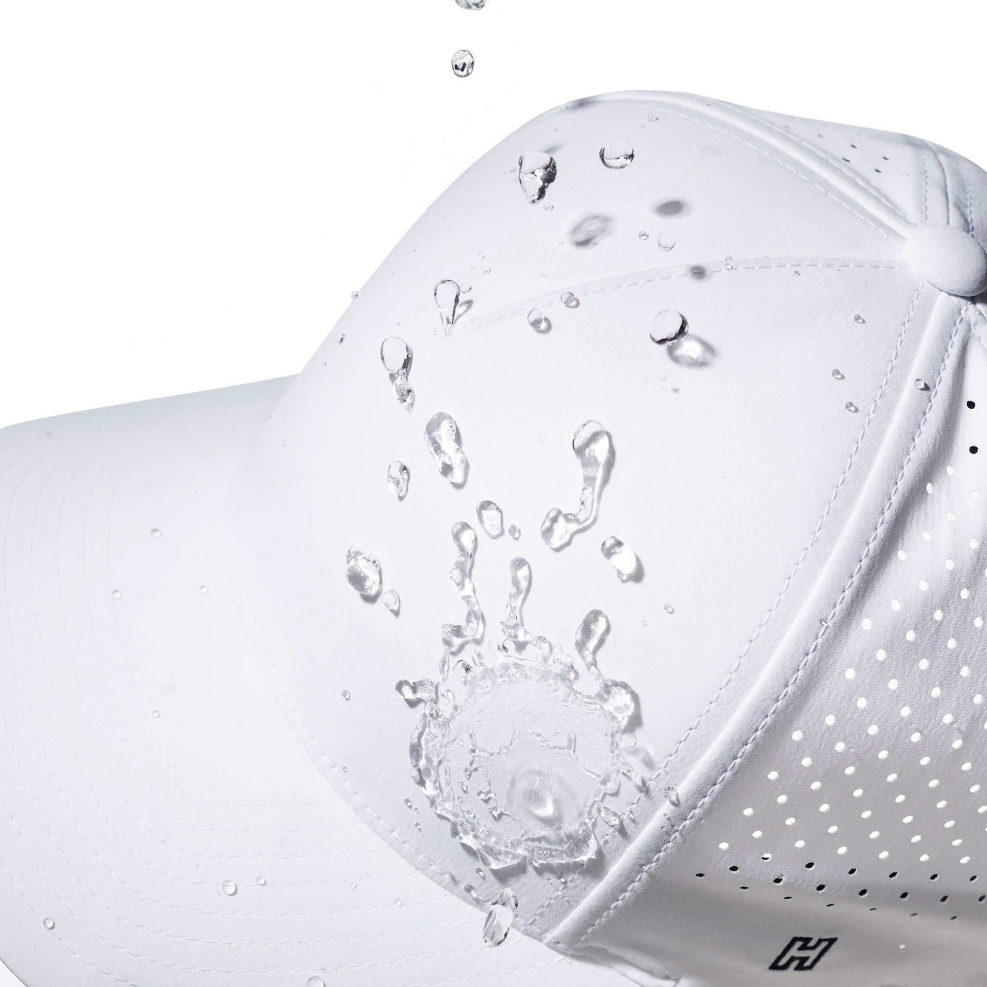White performance hat with water droplets splashing onto it against a white background