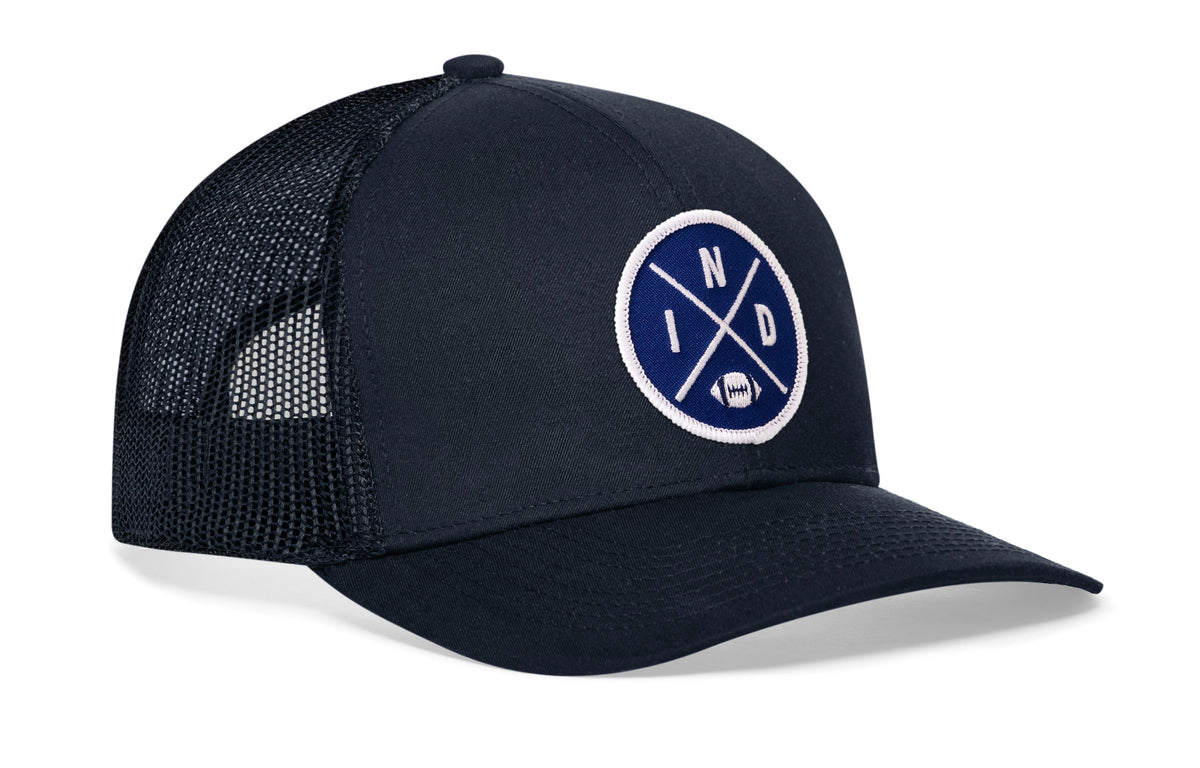 navy trucker hat viewed from the right side, showcasing a bold blue and white embroidered X patch prominently displayed on the front