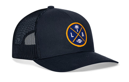 navy trucker hat viewed from the right side, showcasing a bold dark blue and yellow embroidered X patch prominently displayed on the front