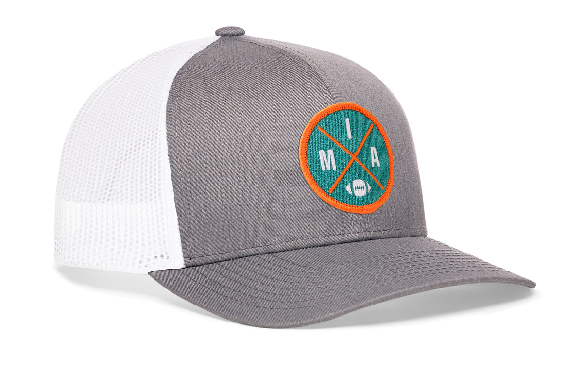 gray-white trucker hat viewed from the right side, showcasing a bold aqua and orange embroidered X patch prominently displayed on the front