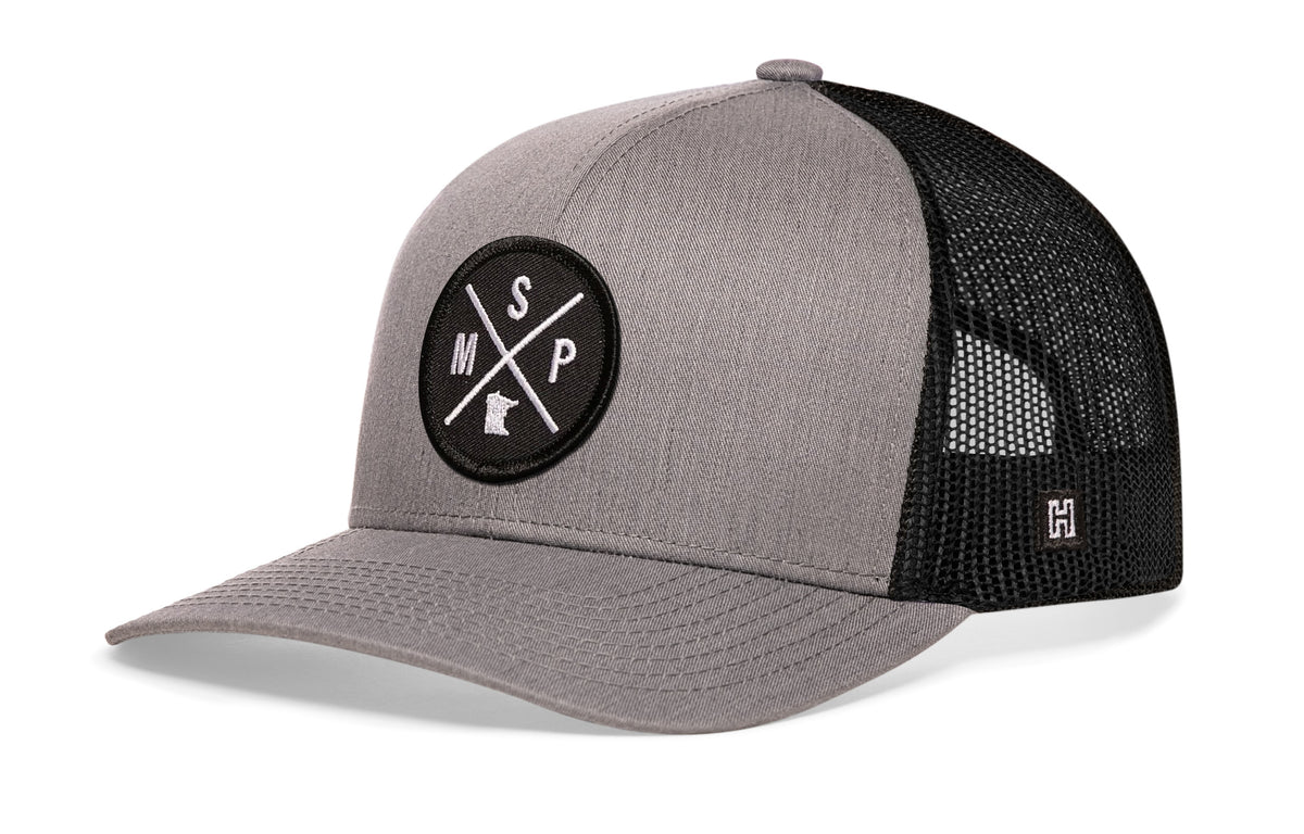 Minneapolis-St Paul Trucker Hat, gray-black snapback showing Haka brandmark on left side of cap.