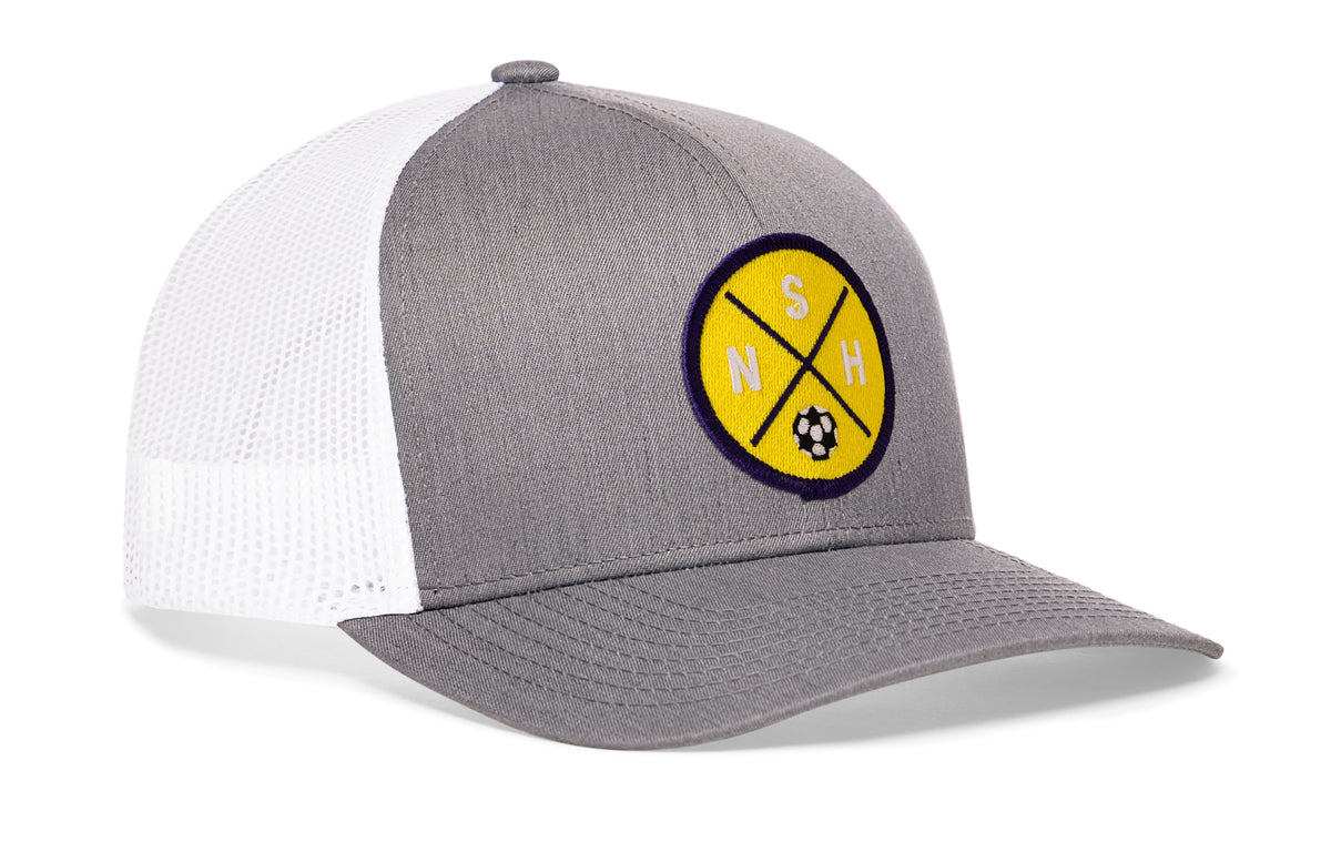 gray-white trucker hat viewed from the right side, showcasing a bold yellow and blue embroidered X patch prominently displayed on the front