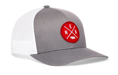 gray-white trucker hat viewed from the right side, showcasing a bold red and white embroidered patch prominently displayed on the front