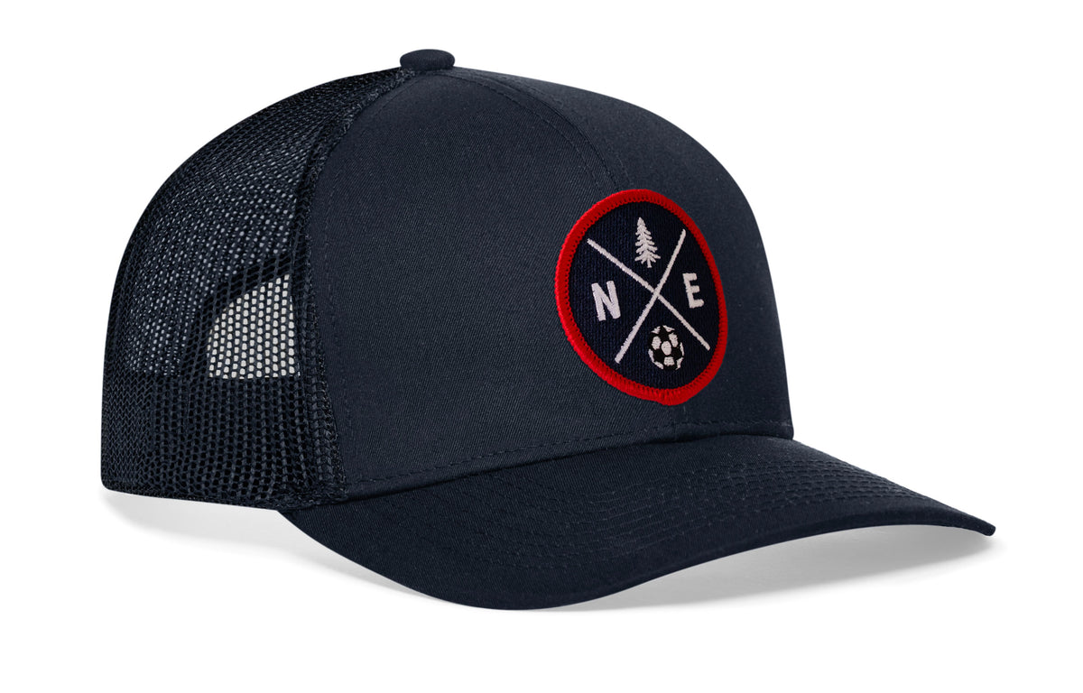 navy trucker hat viewed from the right side, showcasing a bold red and blue embroidered X patch prominently displayed on the front