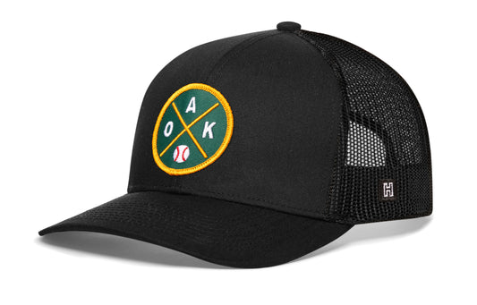 Oakland Baseball Trucker Hat, black snapback showing Haka brandmark on left side of cap.