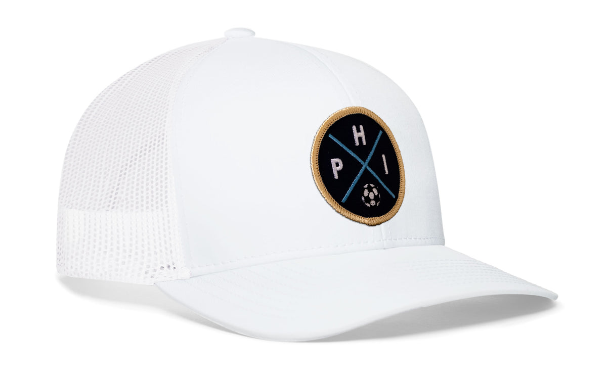 white trucker hat viewed from the right side, showcasing a bold navy and gold embroidered X patch prominently displayed on the front