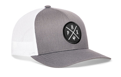 gray-white trucker hat viewed from the right side, showcasing a bold black and white embroidered X patch prominently displayed on the front
