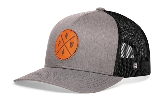 Pacific Northwest Trucker Hat, gray-black snapback showing Haka brandmark on left side of cap.