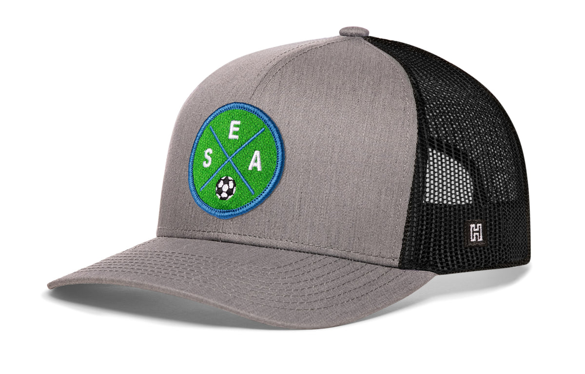 Seattle Soccer Trucker Hat, gray-black snapback showing Haka brandmark on left side of cap.