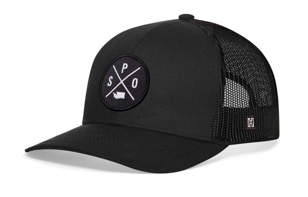 Spokane Trucker Hat, black snapback showing Haka brandmark on left side of cap.