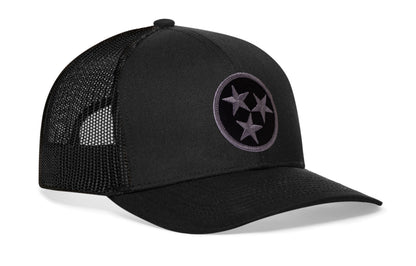 black trucker hat viewed from the right side, showcasing a bold black and gray embroidered flag patch prominently displayed on the front