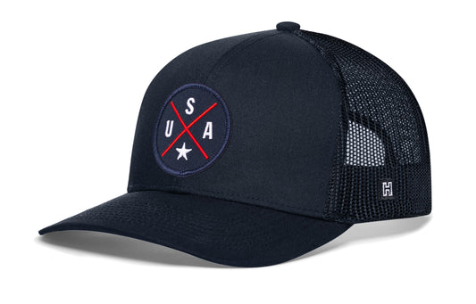 USA X Trucker Hat, navy snapback showing Haka brandmark on left side of cap.