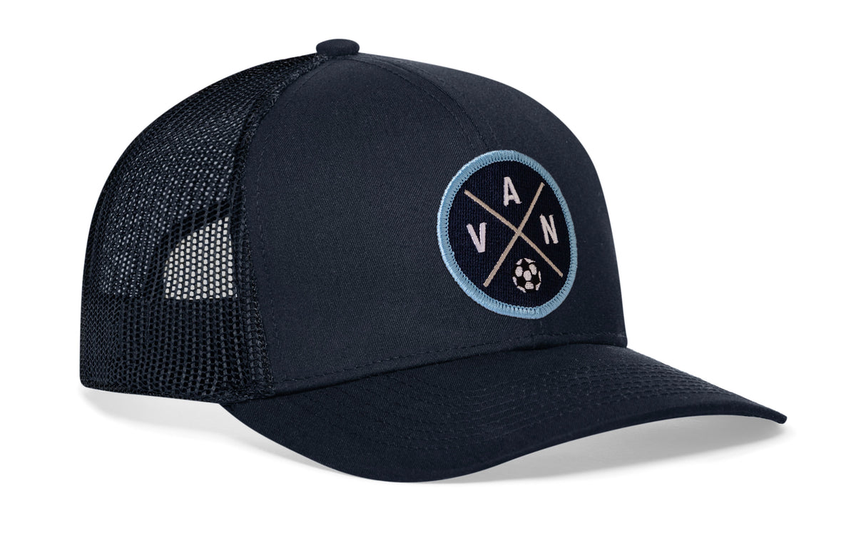 navy trucker hat viewed from the right side, showcasing a bold blue and white embroidered X patch prominently displayed on the front