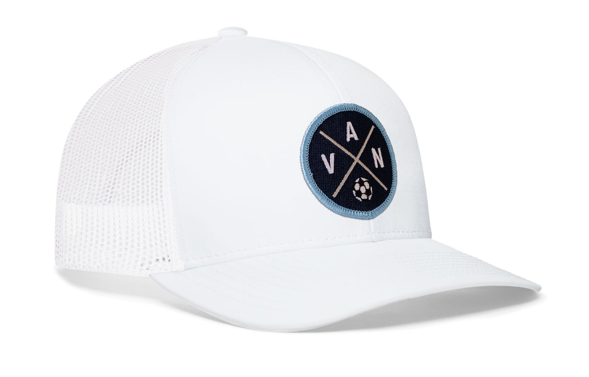 white trucker hat viewed from the right side, showcasing a bold blue and white embroidered X patch prominently displayed on the front