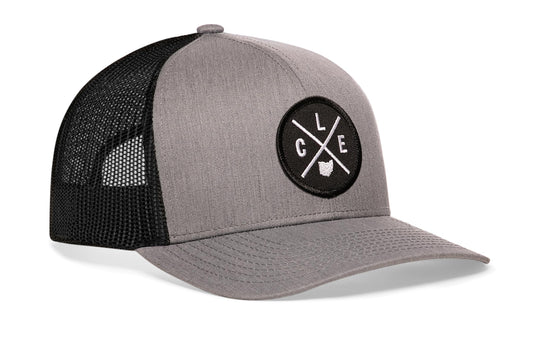 Gray-Black trucker hat viewed from the right side, showcasing a Cleveland CLE X Embroidered Circle Patch prominently displayed on the front