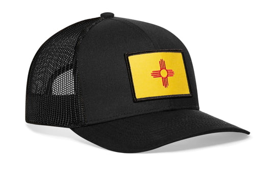 Black trucker hat viewed from the right side, showcasing a New Mexico Woven Rectangle Patch prominently displayed on the front