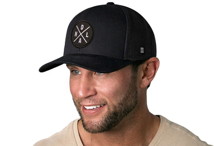 Black trucker hat worn by a male model viewed from the left side and features a New Orleans NOLA X Embroidered Circle Patch displayed on the front panel. The hat has a classic mesh back design and a curved structured bill