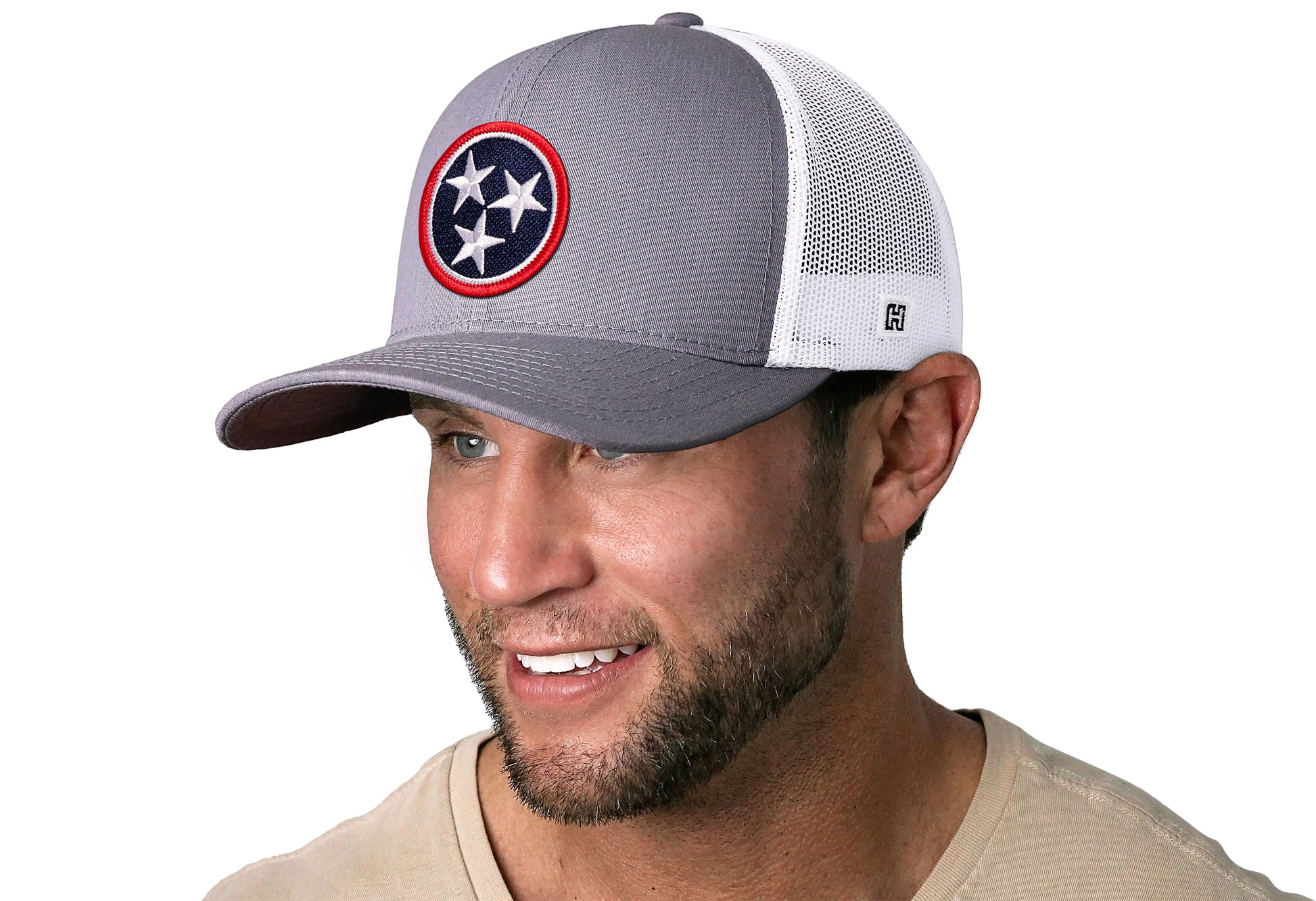 Gray-White trucker hat worn by a male model viewed from the left side and features a Tennessee Embroidered Flag Patch displayed on the front panel. The hat has a classic mesh back design and a curved structured bill